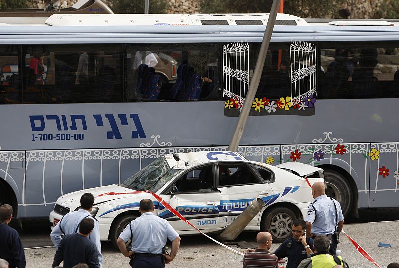 Policías israelíes junto a autobús y coche contra el que ha impactado la excavadora