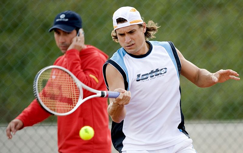 David Ferrer golpea la bola en presencia de su capitán, Albert Costa, durante los entrenamientos antes de su debut contra Djokovic.