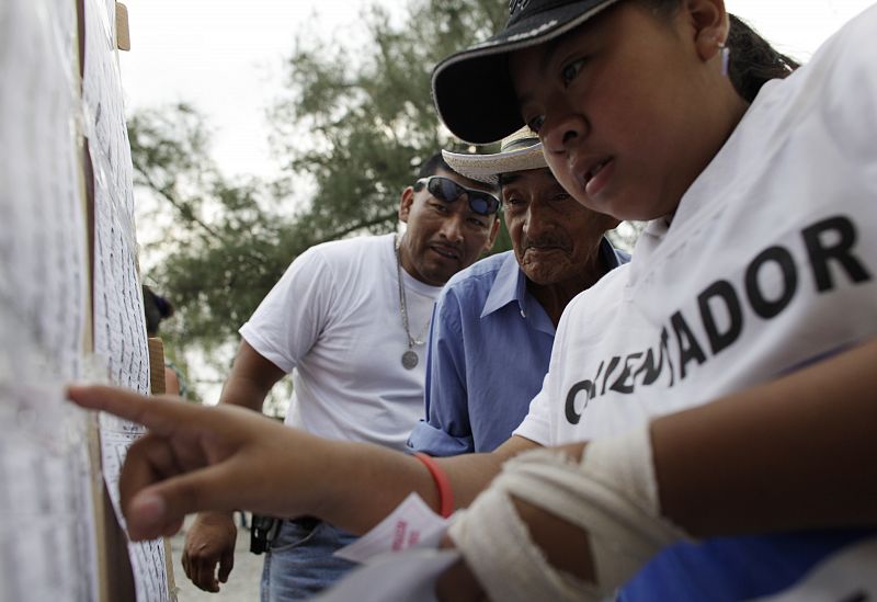 Salvadoreños buscan el número de su mesa electoral en las elecciones presidenciales en Panchimalco.