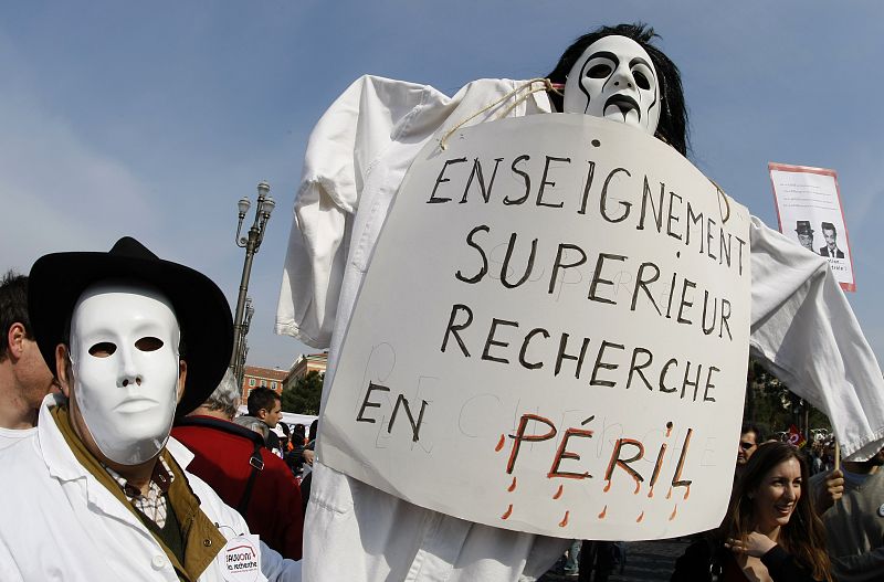 Un investigador universitario sostiene una pancarta con el lema 'la investigación en peligro' en una marcha en Niza