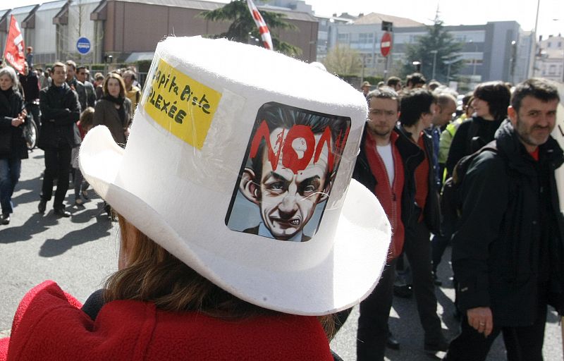 Un manifestante en Lyon lleva un sombrero con una caricatura del Presidente de Francia Nicolas Sarkozy