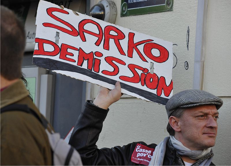Un manifestante en París sostiene una pancarta en la que pide la dimisión de Sarkozy