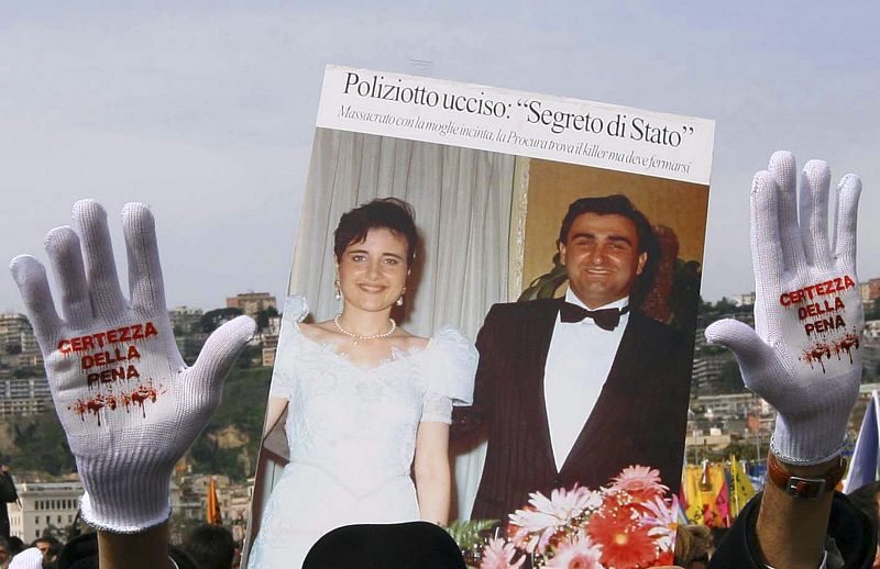 Demonstrator displays gloves with phrase "Punishment must be guaranteed" as he marches in the southern city of Naples