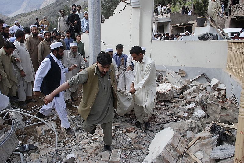 Pakistani tribesmen carry a body recovered from the debris at the site of a suicide blast near Jamrud in the Khyber agency tribal region