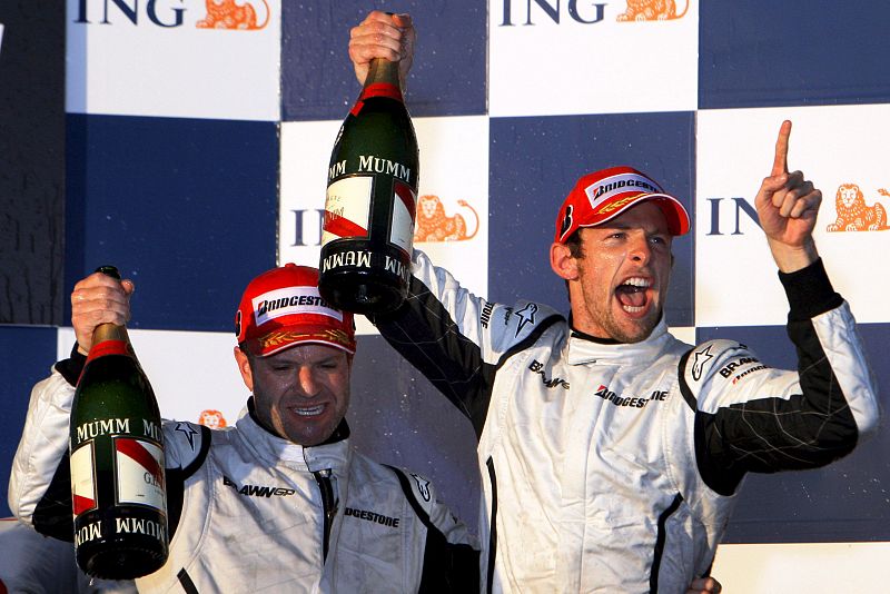 El piloto británico Jenson Button de Brawn GP (d) y su compañero de equipo, el brasileño Rubens Barrichello (i), celebran en el podio el primer y segundo puesto conseguido.