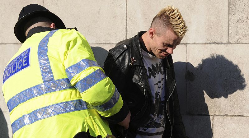 Un oficial de policía registra a uno de los activistas en los alrededores del Banco de Inglaterra