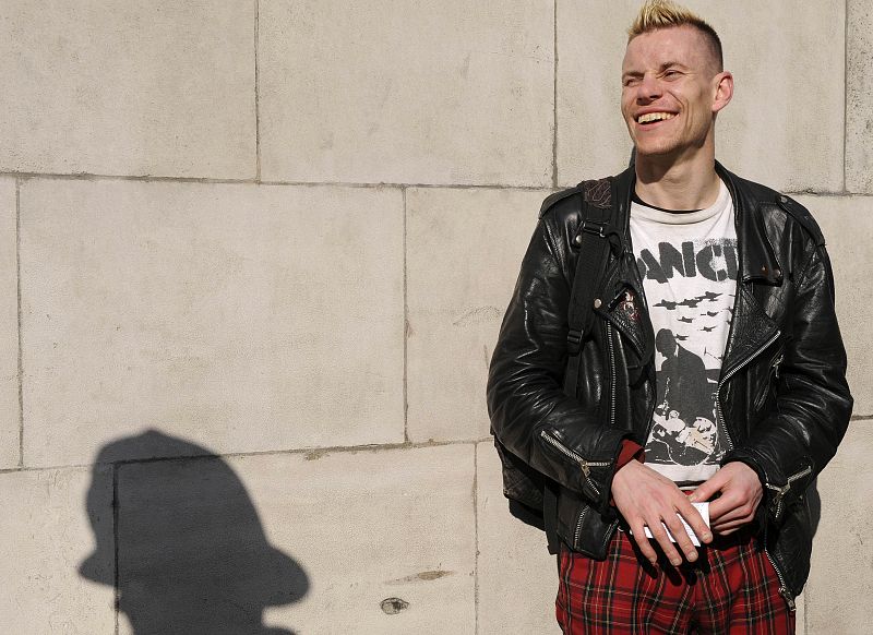 Un manifestante antisistema ríe después de haber sido registrado por un oficial de policía