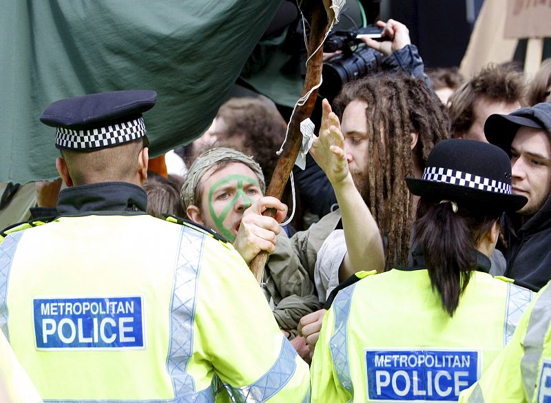 Un grupo de activistas anticapitalistas y contrarios al cambio climático grita consignas ante la policía