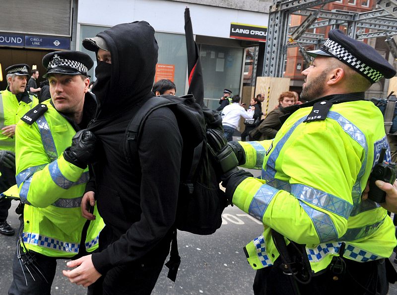 Varios policías empujan a un activista que participaba en una concentración en el distrito financiero de la capital británica