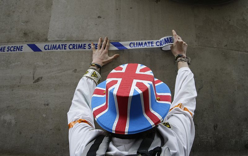 Un manifestante pega una cinta en un muro cerca del Banco de Inglaterra con el lema "escena del crimen climático".