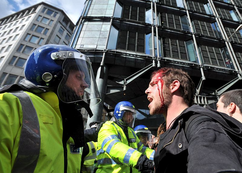 Un manifestante herido discute con un agente después de una carga policial en Londres.