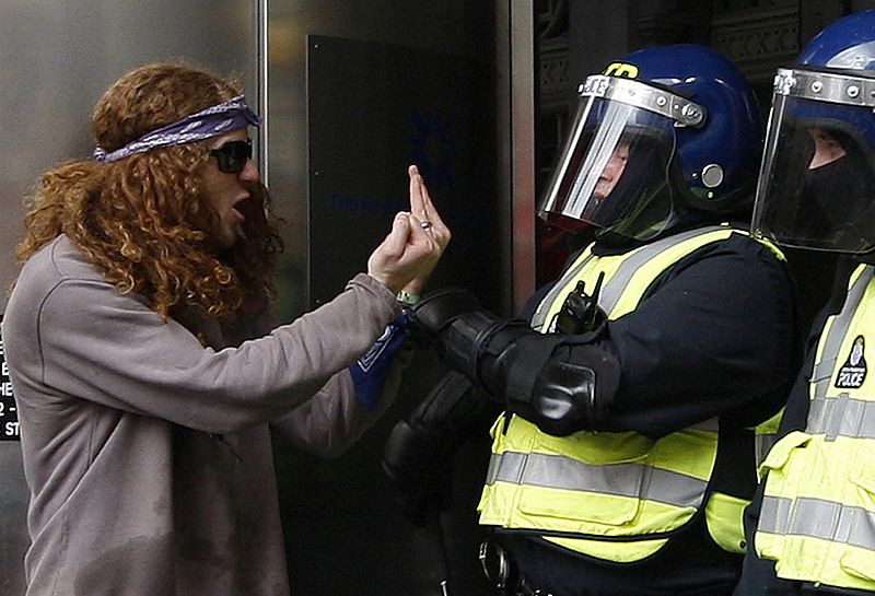 Un manifestante le hace un gesto obsceno a un agente de policía cerca del Banco de Inglaterra en Londres.