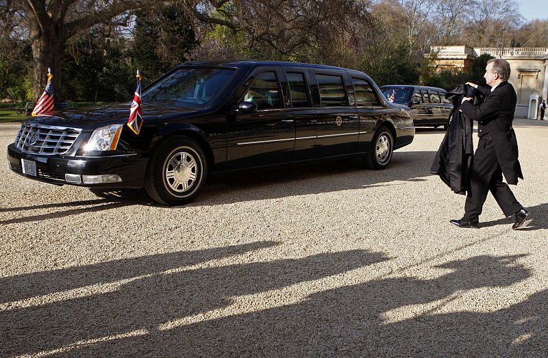 Un empleado del Palacio de Buckingham lleva el abrigo de Obama a la limusina del presidente de Estados Unidos