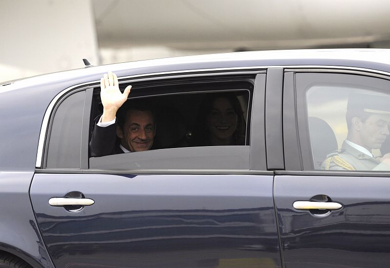 El presidente francés, Nicolas Sarkozy, y su esposa, Carla Bruni, saludan desde el coche