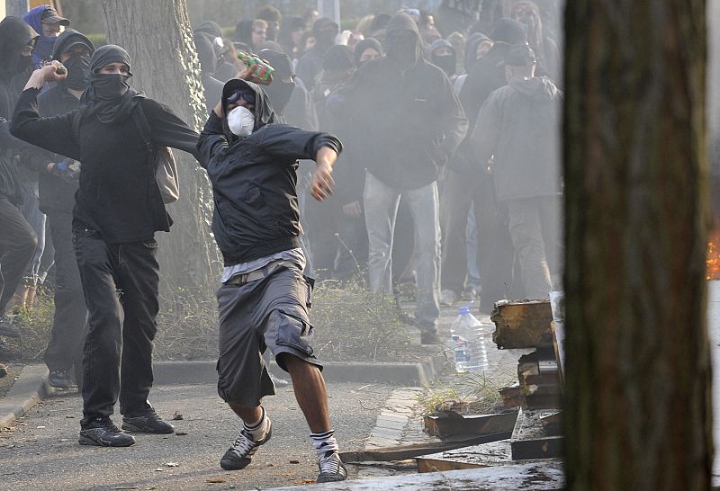 Hooded anti-NATO demonstrators throw bottles during clashes with French riot police in the southern suburbs of Strasbourg