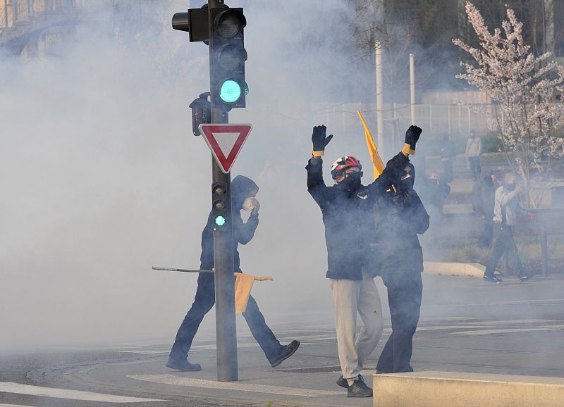 Masked anti-NATO protesters stand in a cloud of teargas after being stopped by police  from going to downtown Strasbourg