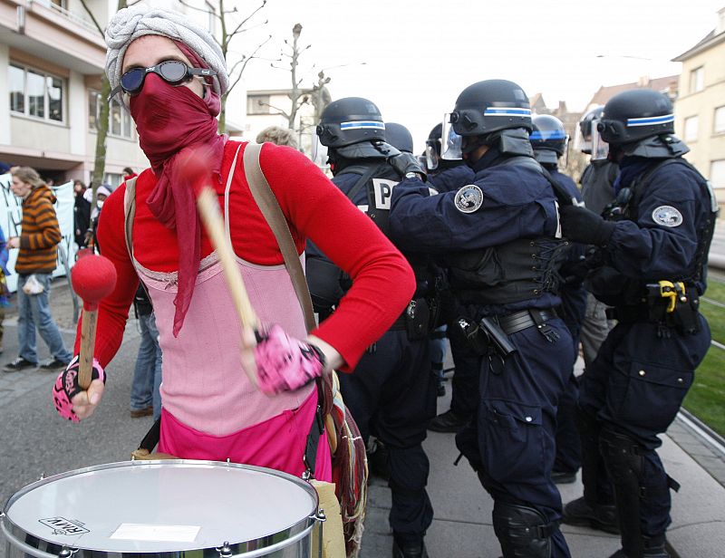 An anti-NATO demonstrator plays the drums as French riot police block a group staging protest next to the congress centre in Strasbourg