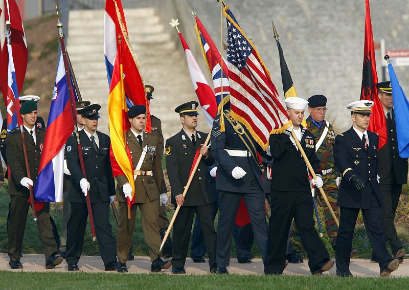 Soldiers of different NATO countries carry flags as they arrive for a minute of silence ceremony in Strasbourg