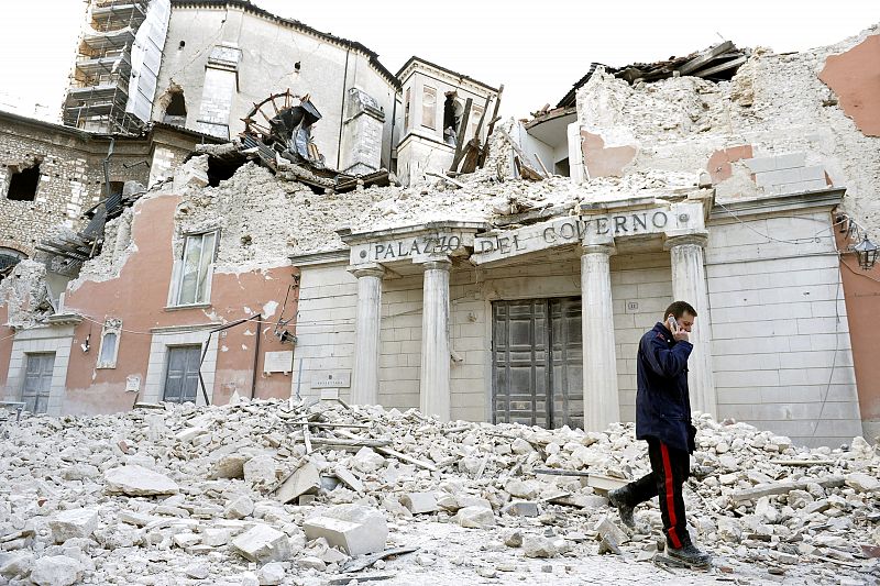 An Italian military carabinieri walks on debris past destroyed buildings after an earthquake, in downtown Aquila