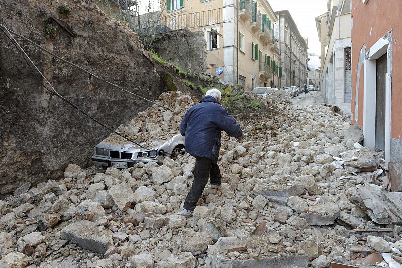 A man walks on debris as he looks for his relatives after an earthquake, in downtown Aquila