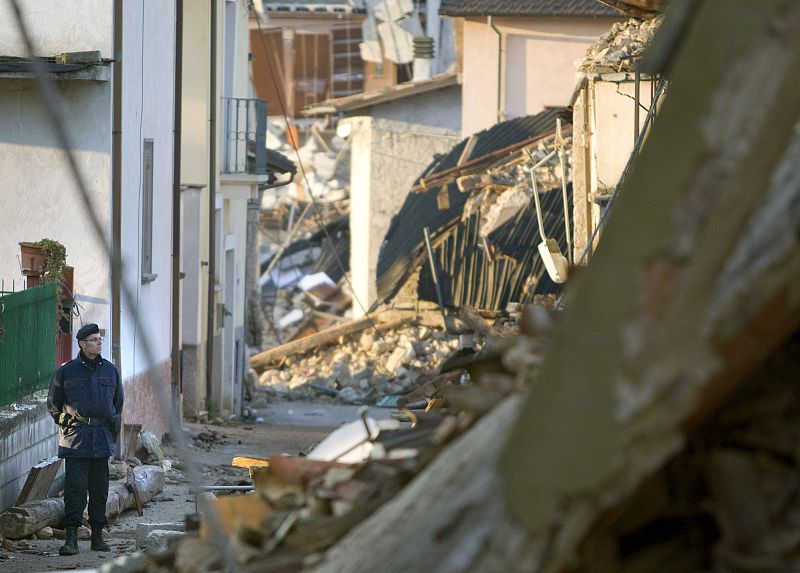 Un agente de policía vigila la zona destrozada por el terremoto en la localidad italiana de Onna.