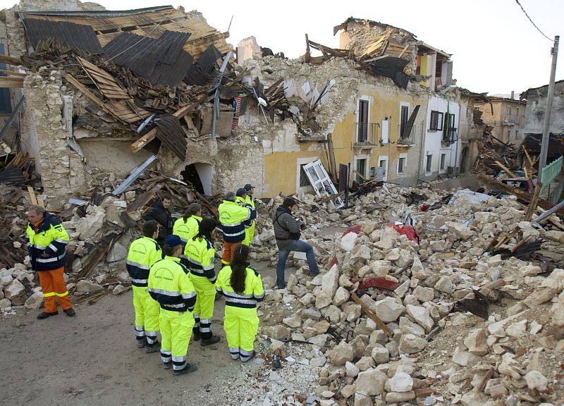 Trabajadores de los equipos de rescate observan los destrozos del terremoto en Onna.