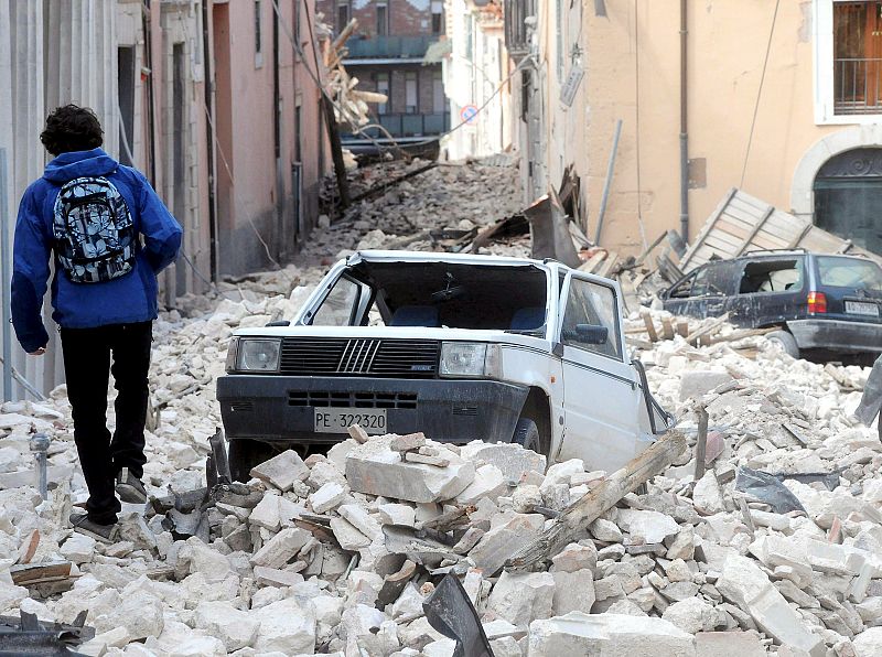 Un joven camina entre los escombros que el terremoto ha dejado en L'Aquila, en Italia.