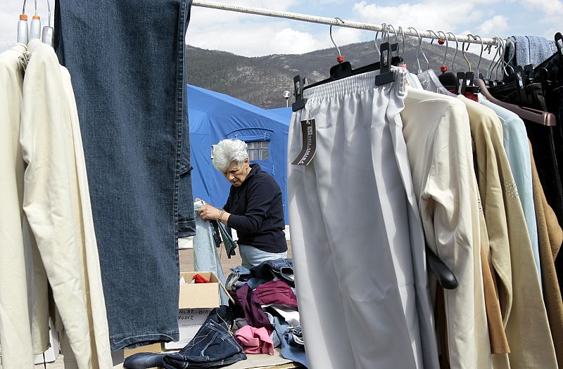 Una mujer ordena su ropa en el campo de víctimas del terremoto de L'Aquila.