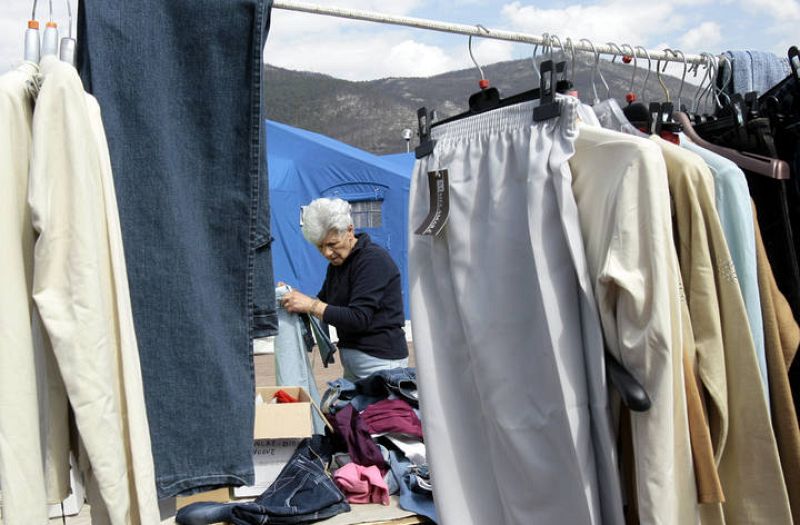 Una mujer ordena su ropa en el campo de víctimas del terremoto de L'Aquila.