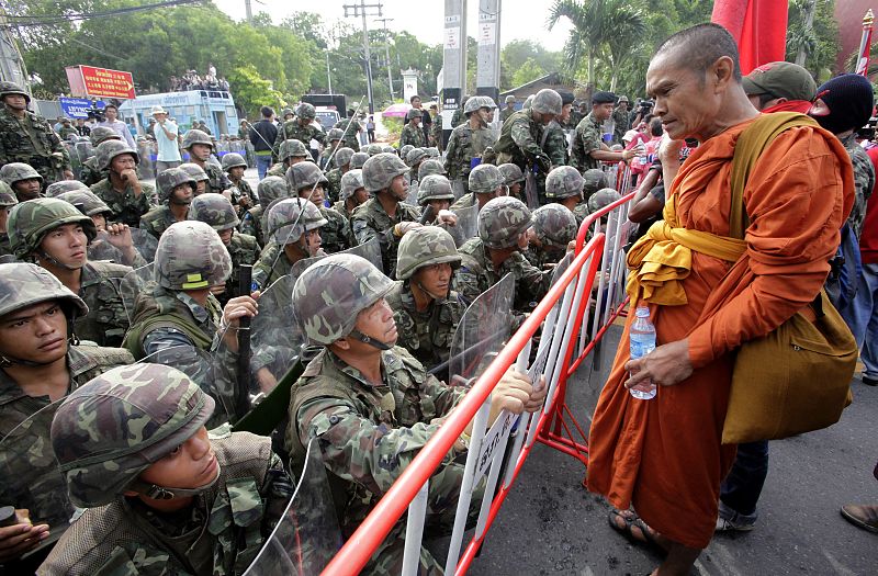 Un monje budista habla con un policía tailanés.