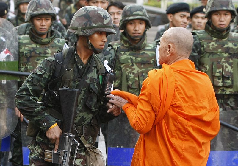 A Buddhist monk talks to a soldier in Bangkok