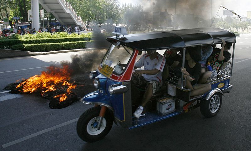 A 'tuk-tuk' passes burning tyres torched by supporters of ousted Thai PM Thaksin in Bangkok