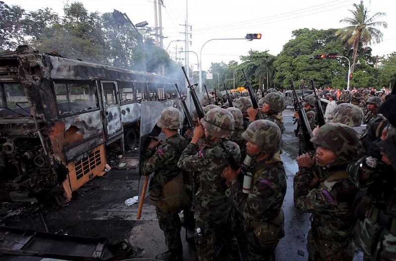 Soldados tailandeses toman posiciones frente a un autobús incendidado.