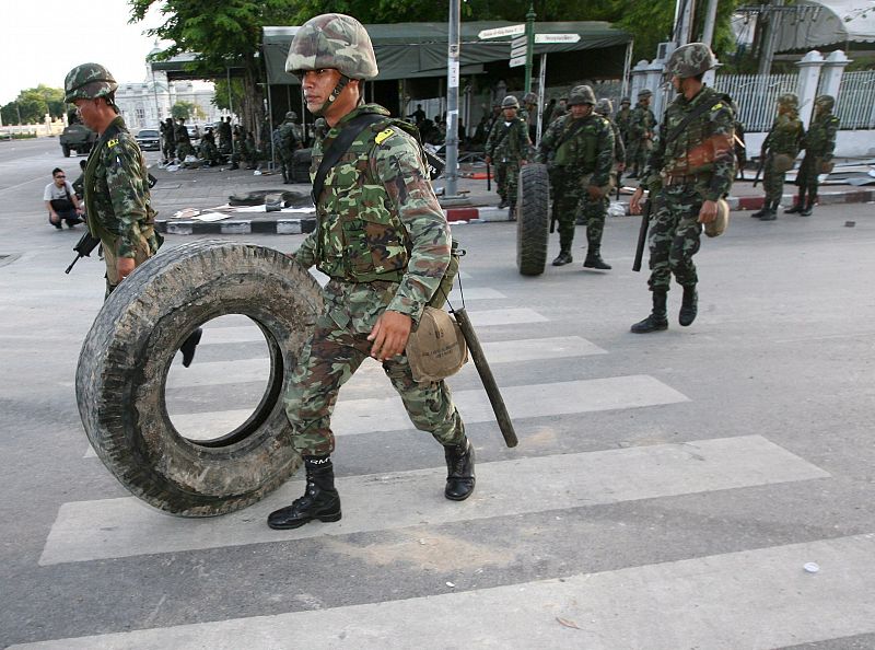 Soldados tailandeses mueven llantas para hacer una barricada en las afueras de la sede del Gobierno en Bangkok.