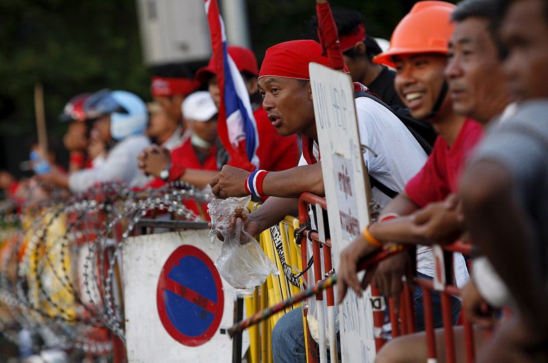 Los 'camisas rojas' miran hacia una barricada, mientras esperan un nuevo enfrentamiento con las fuerzas del orden. En el país asíatico han decretado el estado de excepción.