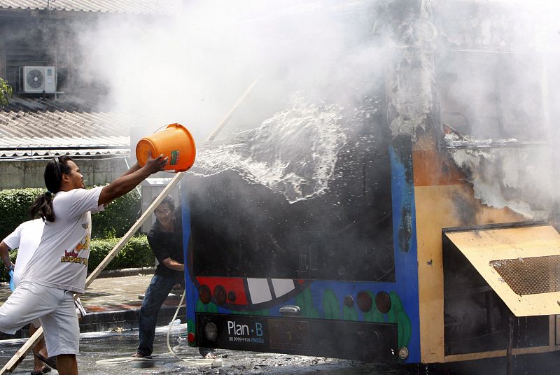 Varios residentes intentan apagar las llamas de uno de los autobuses incendiados durante la revuelta.