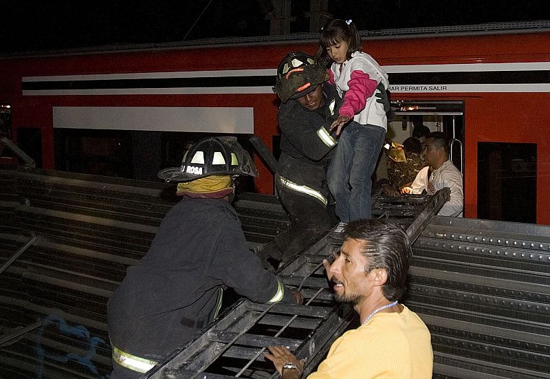 Los bomberos rescatan a una niña. Los cuerpos de emergencias se afanan en liberar a los atrapados en los trenes siniestrados.