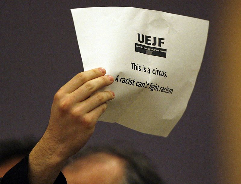 A protestor displays a paper as Iran's President Ahmadinejad addresses the High Level segment of the Durban Review Conference on racism at the United Nations European headquarters in Geneva