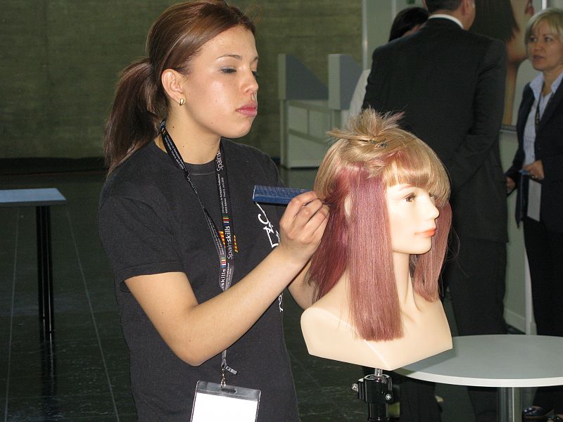 Una de las participantes peina a un maniquí en las pruebas de peluquería.
