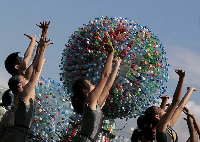 Bailarines filipinos frente a escultura hecha con productos reciclados en Filipinas