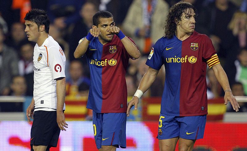 Alves y Puyol protestan al árbitro, acusando a Villa de haberse tirado en el área.