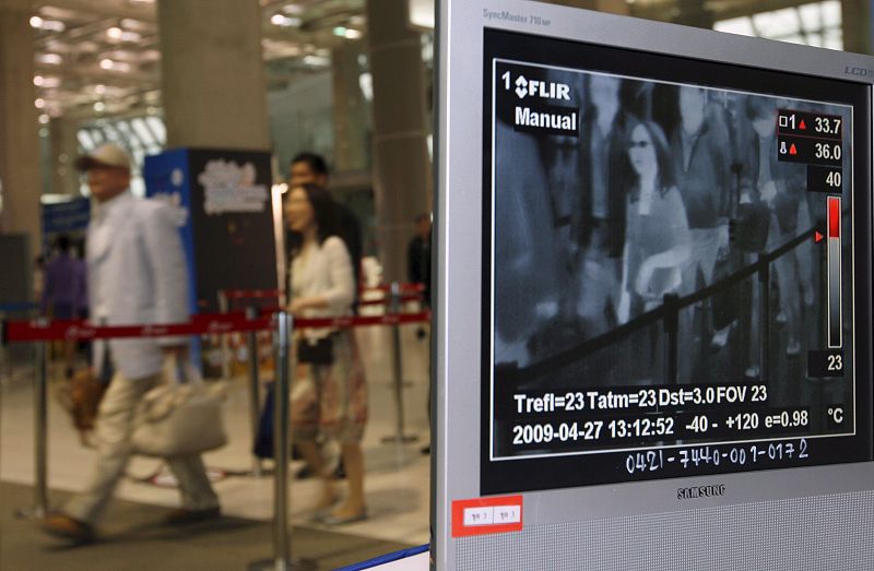 Un hombre realiza un monitoreo a los pasajeros con un escaner termal en el aeropuerto Suvarnabhumi de Bangkok