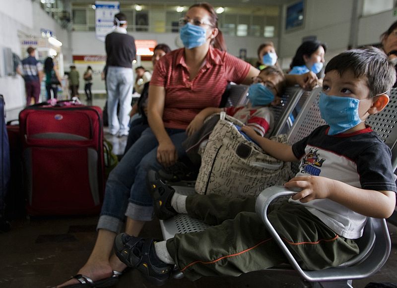 Mujeres y niños con mascarilla esperan el autobús en Ciudad de México