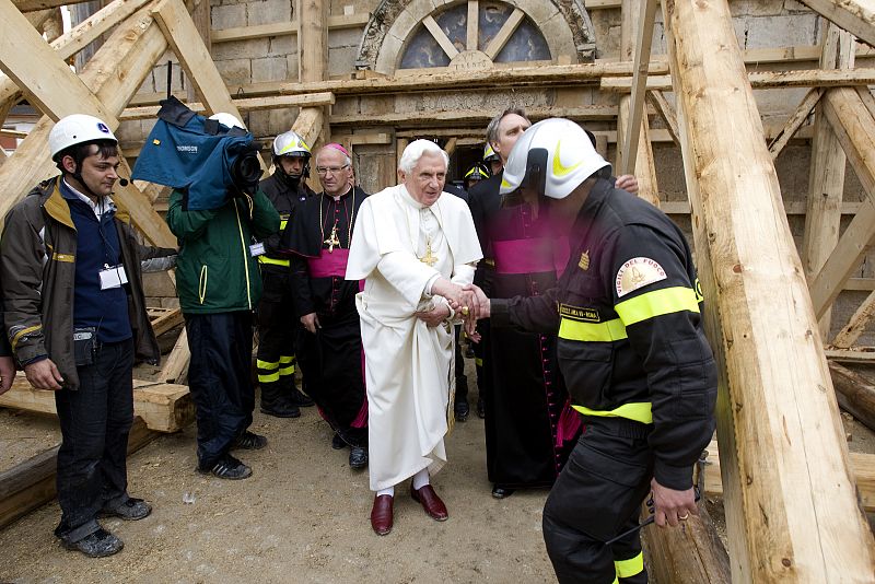 Pope Benedict XVI greets a fireman after visiting a little church in the destroyed village of Onna