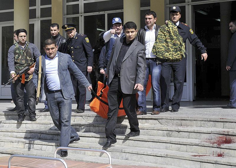 The body of a victim of a shooting at a university is carried down bloodstained steps to a van in Baku