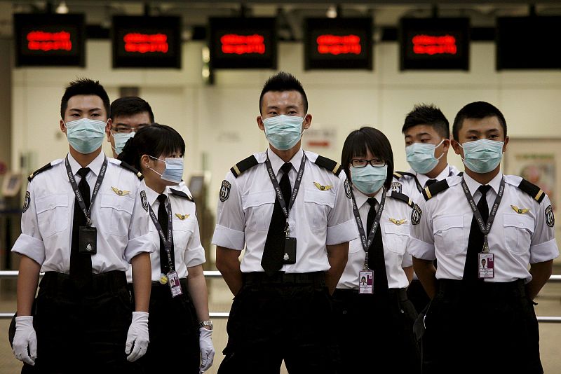 Varios operarios del Departamento de Salud esperan antes de un cambio de turno en el aeropuerto de Hong Kong, en China.