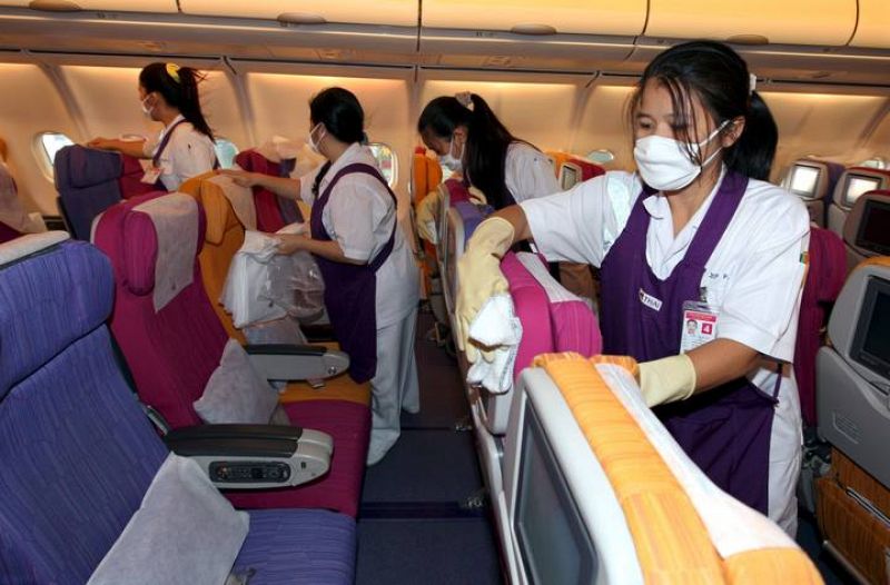 Varias operarias limpian la cabina de pasajeros de un avión de Thai Airways procedente de Los Ángeles.