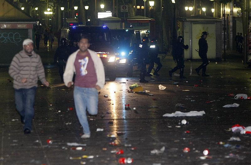 Algunas personas corren por las calles de Barcelona para escapar de los Mossos d' Esquadra.