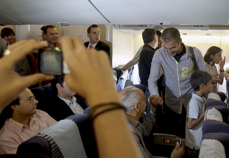 Guardiola saluda a algunos aficionados a su llegada al avión.