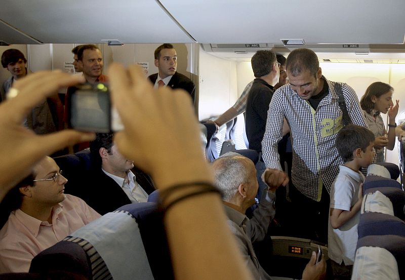Guardiola saluda a algunos aficionados a su llegada al avión.